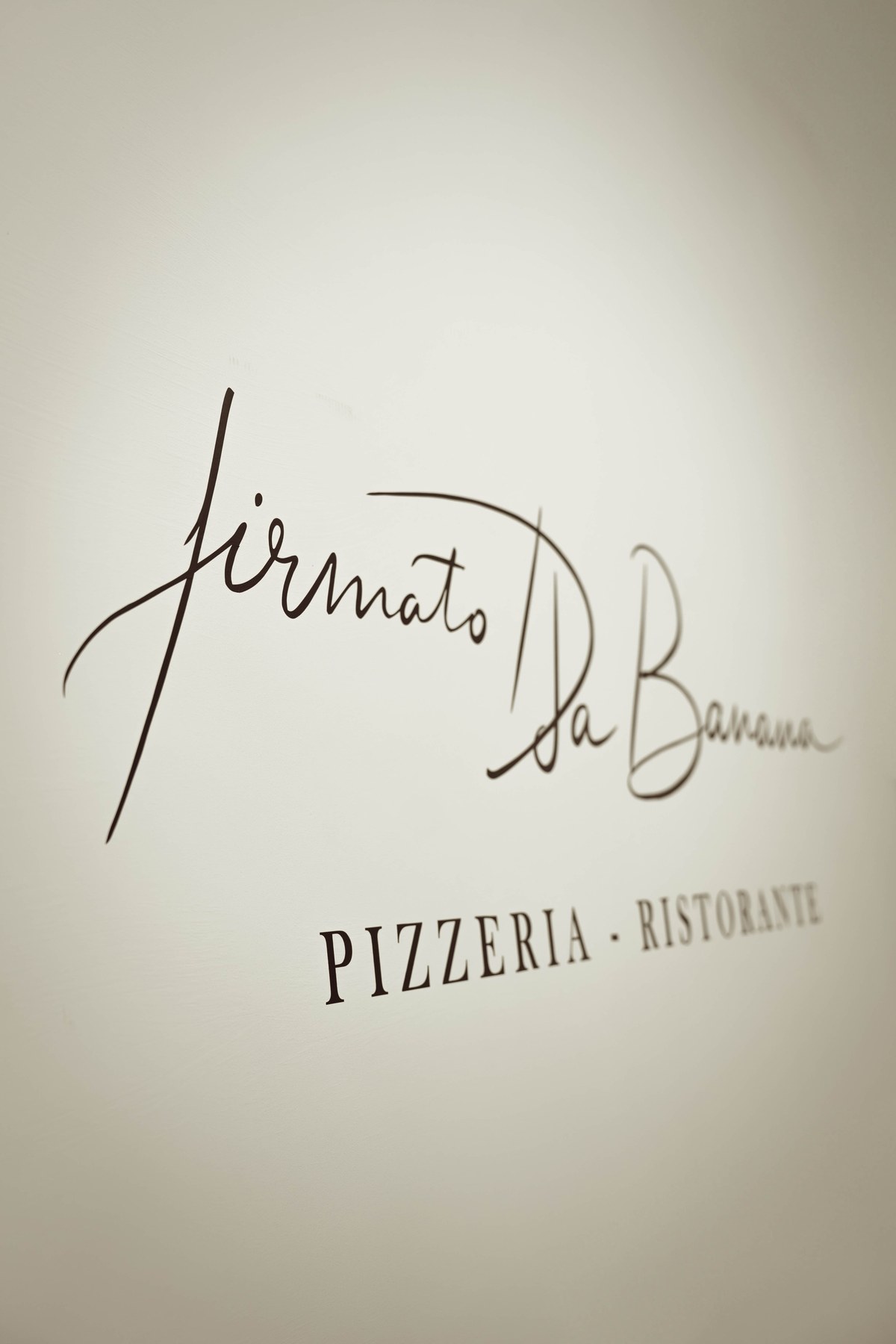 La firma del ristorante sulla parete chiara del locale